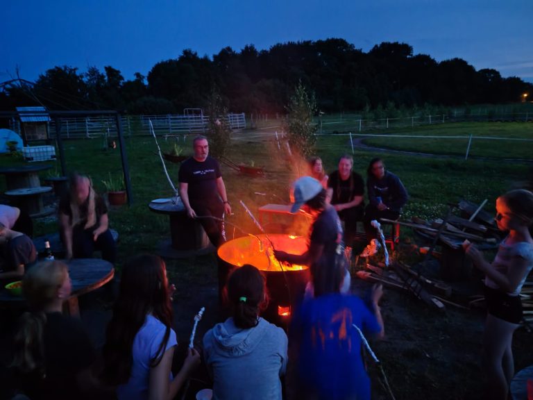 Gruppe sitzt abends am Lagerfeuer